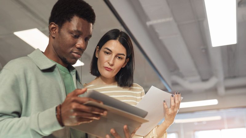 Dos profesionales revisando documentos en una tableta digital dentro de una oficina